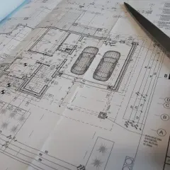 Projekt architektoniczno budowlany domu z garażem, z widokiem na plany i nożyczki.