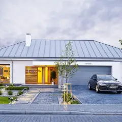 Nowoczesny projekt domu z podjazdem i samochodem. Elegancka bryła z drewnianymi elementami i dużymi przeszkleniami.