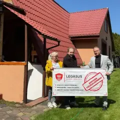 Trzy osoby trzymają baner "Budynek zalegalizowany". Pomagają w procesie jak zrobić odbiór domu po 20 latach.