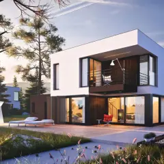 Super nowoczesne domy w otoczeniu lasu. Na tarasie leżaki, stolik z krzesłami i palenisko. W oddali widać kolejne modernistyczne budynki.