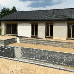 Budowa domu 3e w toku. Fundamenty i ściany parteru z bloczków betonowych, gotowe okna.
