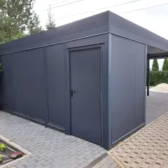 Nowoczesny budynek gospodarczy z wiatą, wykonany z ciemnoszarego metalu, z drzwiami i zadaszeniem.
