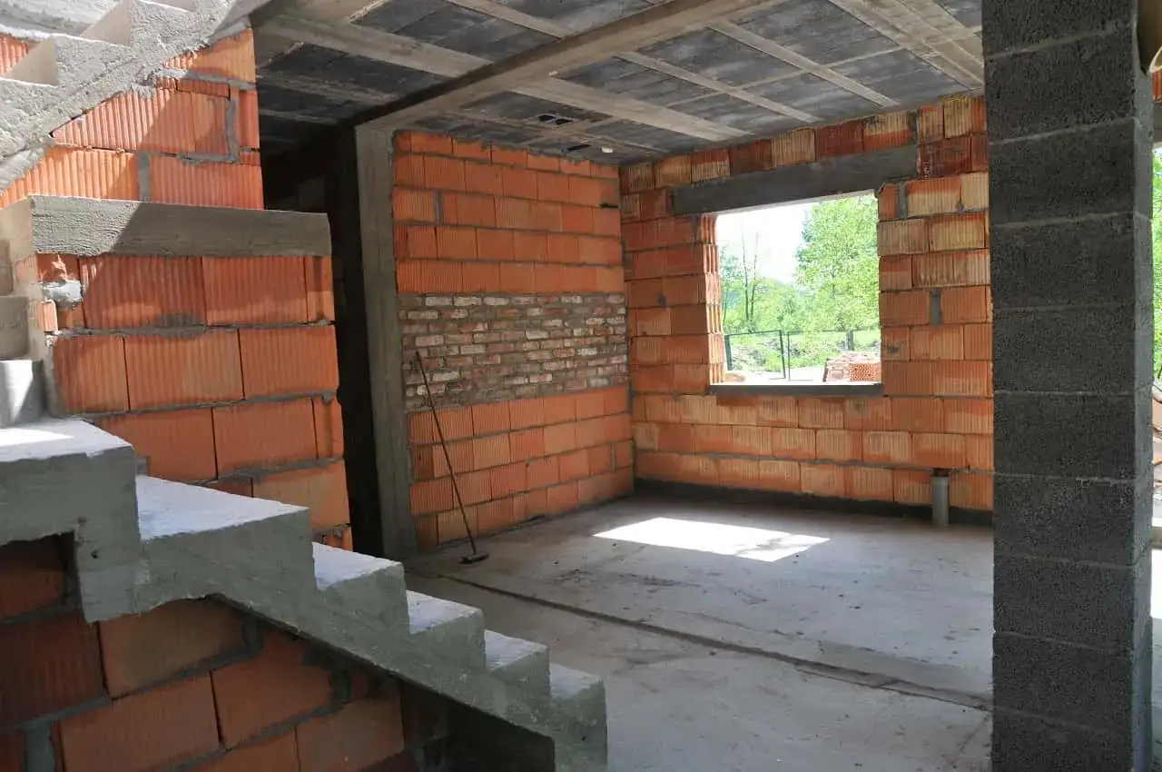 Budynek gospodarczy w trakcie samowolnego przekształcenia na mieszkalny. Widać schody, ściany z pustaków ceramicznych i betonowy strop.