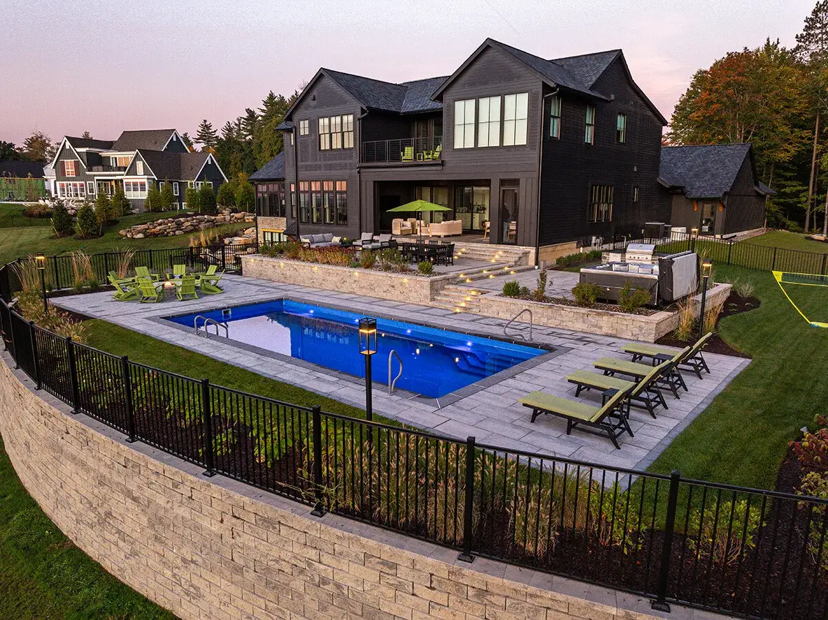Nowoczesny basen przy domu z podświetlaną wodą, tarasem, jacuzzi i miejscem do grillowania. Idealne miejsce na relaks i spotkania.